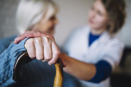 Nurse helping senior with cane