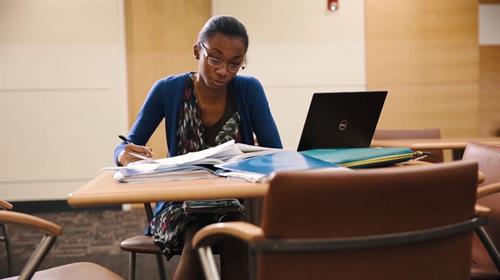 Young woman sitting at table with computer.